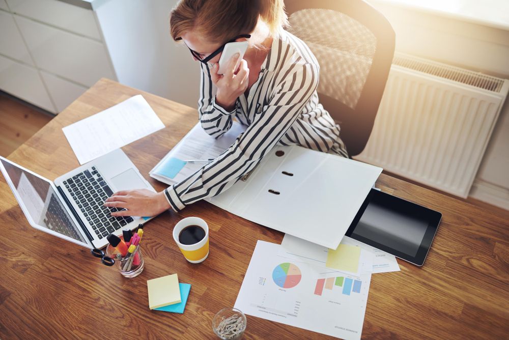 Top view of woman taking phone in home office with coffee
