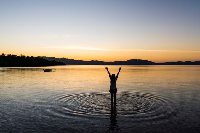 Female standing in lake at sunset