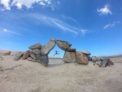 Person jumping near gray rock formation