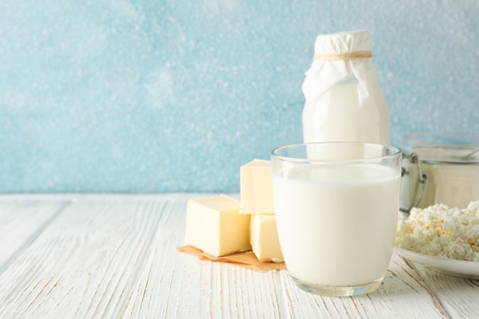 Different dairy products on wooden table against blue background, copy space