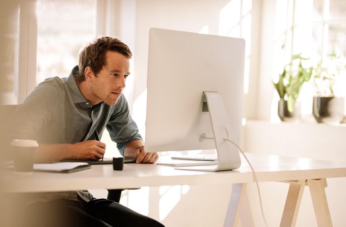 Man looking closely at computer screen while sitting at desk