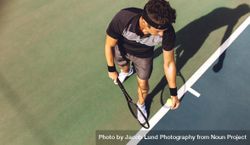 Top view of a young tennis player with racket ready to serve a tennis ball 0K6z1b