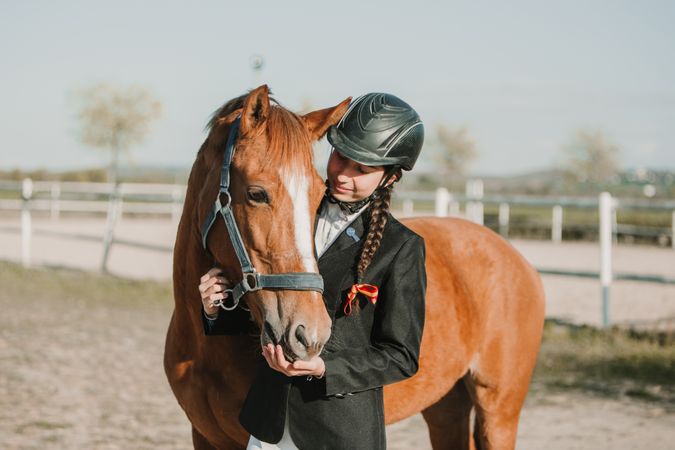 Woman in jockey outfit standing with horse