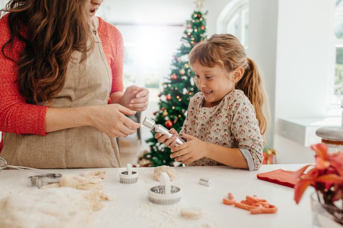 Mother and daughter smiling while making cookies for Christmas