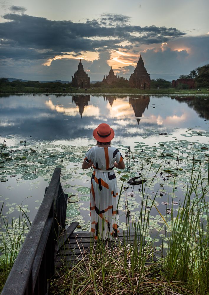 Woman standing at lakeside and enjoying view of Buddhist temples