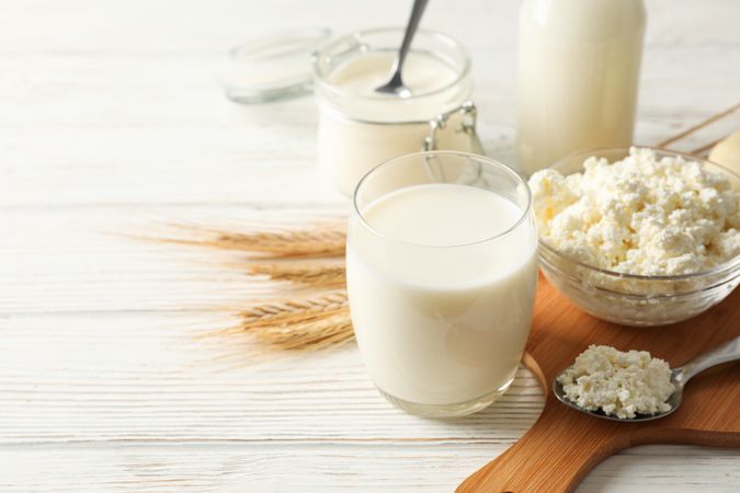 Spikelets of wheat, dairy products and board on wood background, copy space