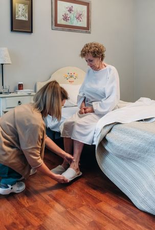 Carer wearing slippers to mature patient