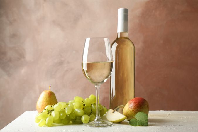 Pears, grape, bottle and glass with wine on blank background, copy space