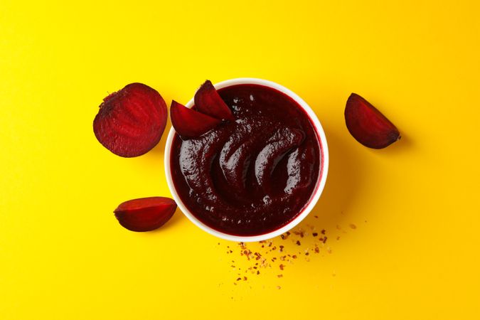 Looking down at bowl of borscht or beetroot soup on yellow table