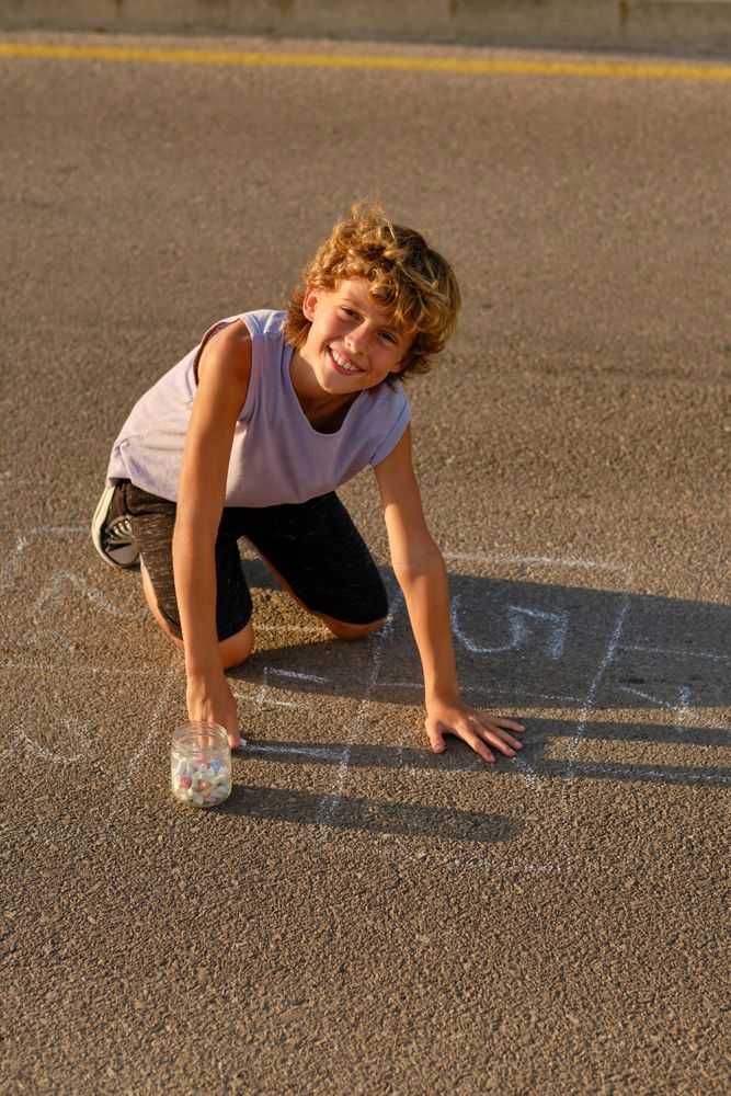 Cheerful boy drawing on asphalt ground