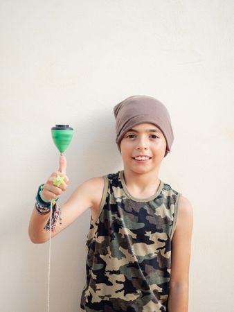 Smiling boy spinning tops on finger and looking at camera