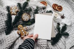Christmas still life with hand holding blank card next to gingerbread cookie