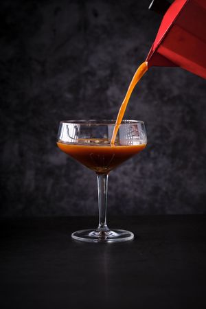 Anonymous barkeeper filling glass with coffee cocktail
