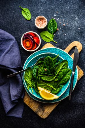 Looking down at fresh spinach salad with lemon slice