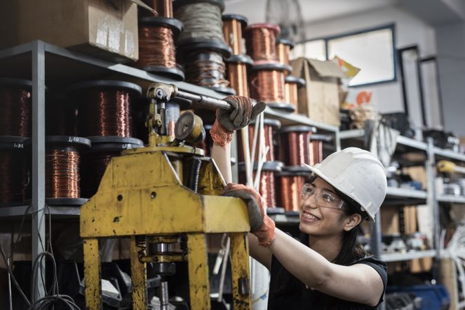 Woman with safety helmet working on heavy machine