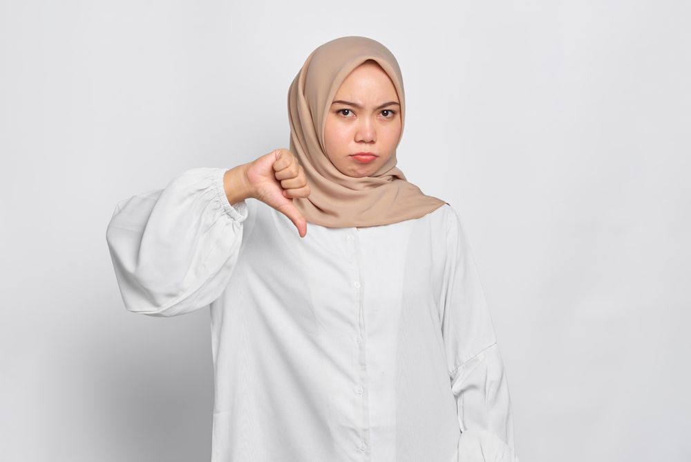 Asian female in headscarf with thumb down