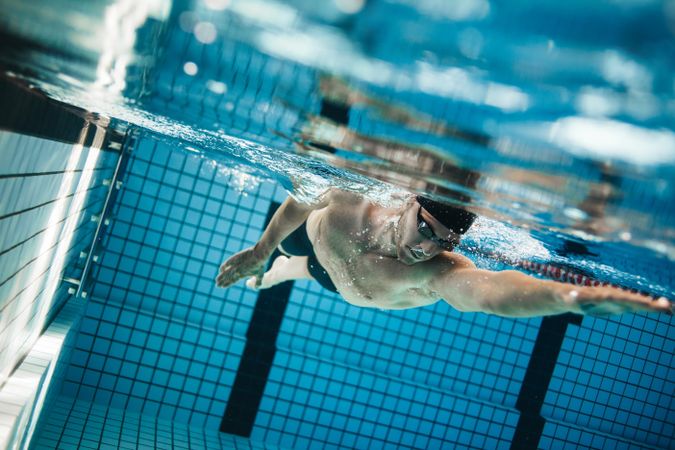 Young man swimming the freestyle stroke in pool