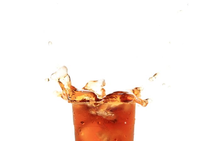 Close Up Splash of Iced Tea on Plastic Cup Isolated on Plain Background.