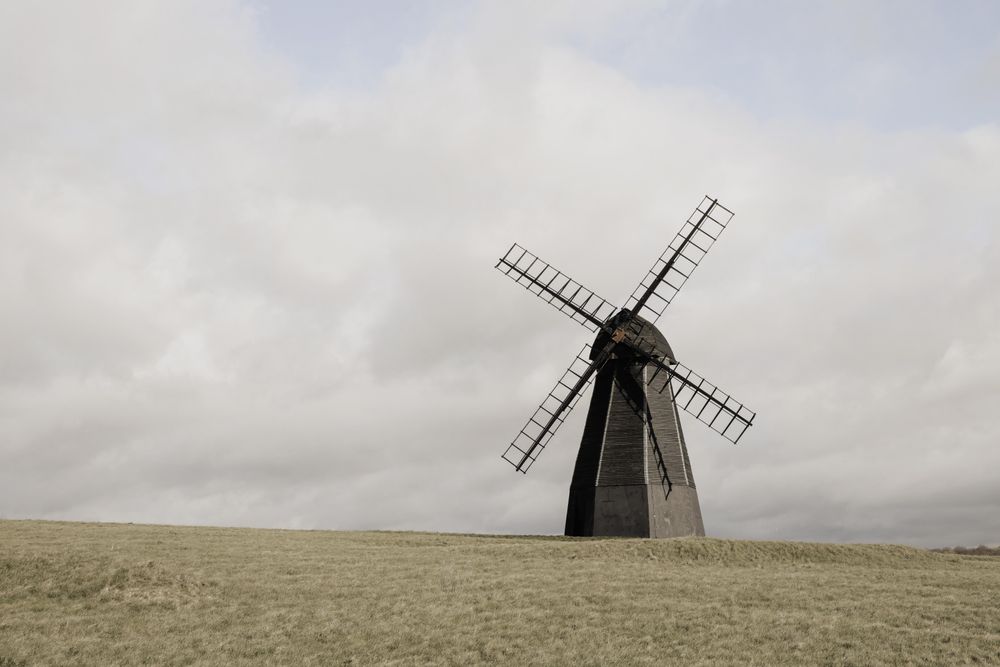 Gray windmill on field under gloomy sky