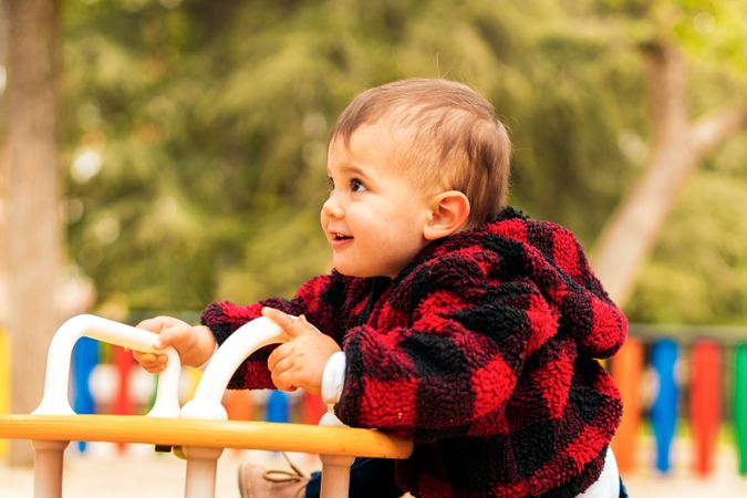 adorable baby boy playing on a playground in a park