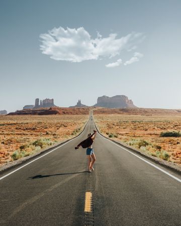 Woman standing in the middle of empty countryside road