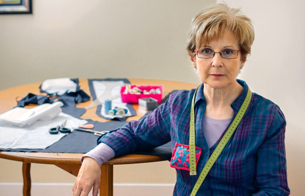 Mature dressmaker posing with sewing materials