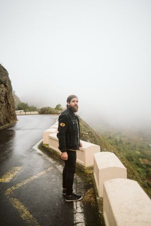Anonymous man standing on cliff near countryside road
