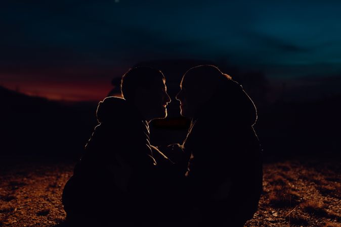 Men hugging and sitting on ground on field at night
