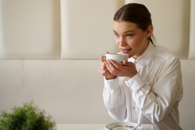 Pensive businesswoman drinking a hot coffee in a cafeteria