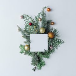 Winter branches arranged with Christmas bauble decorations with light paper card