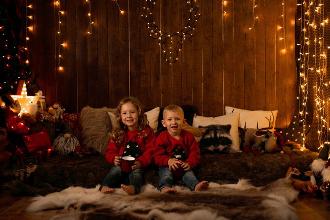 Siblings sitting in a room with christmas decoration