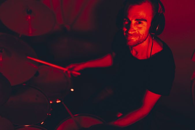 Man with drumsticks playing on drums in redness
