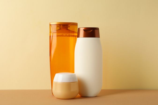 Blank cosmetic bottles on beige background, space for text