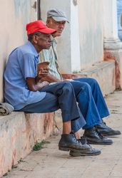 Havana, Cuba - November, 22 2012: Men sitting near shabby wall on street