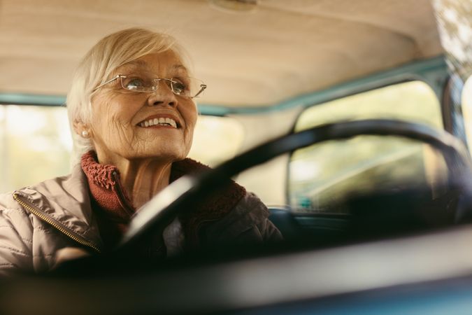 Woman driving car on winter day smiling and driving a vintage car