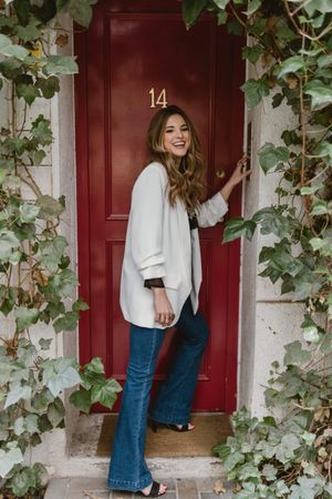 Stylish woman standing near red door