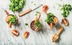 Top view of Moscow mule drinks, knife, citrus reamer, and herbs