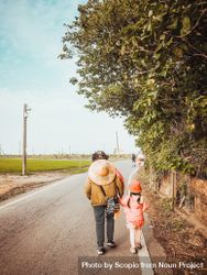 Person and child walking on road near trees 489Vqb