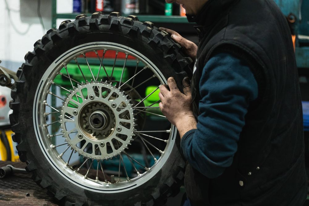 Crop mechanic changing motorbike chain in workshop