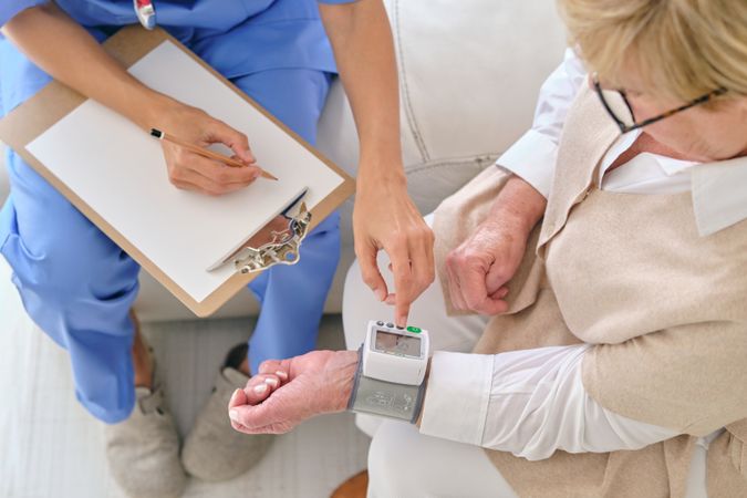 Crop physician measuring pulse rate of patient with tonometer