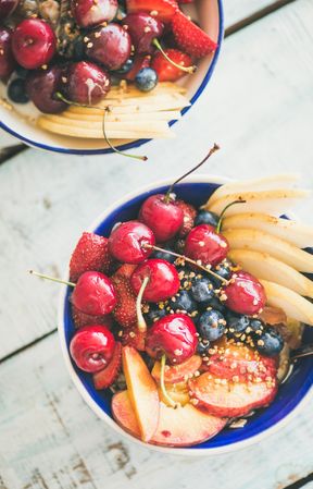 Two bowls of fresh fruit with cherries, peaches, blueberry, strawberries