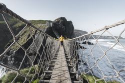 Man crossing rope bridge leading to rocky island