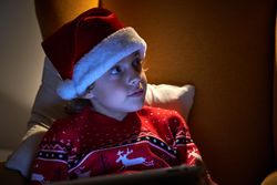 Little boy in Christmas hat sitting in armchair