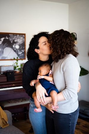 Loving couple holding their baby in the living