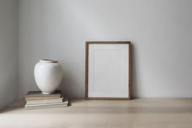 Elegant artistic Scandinavian interior, with empty ceramic vase on vintage books in beige room