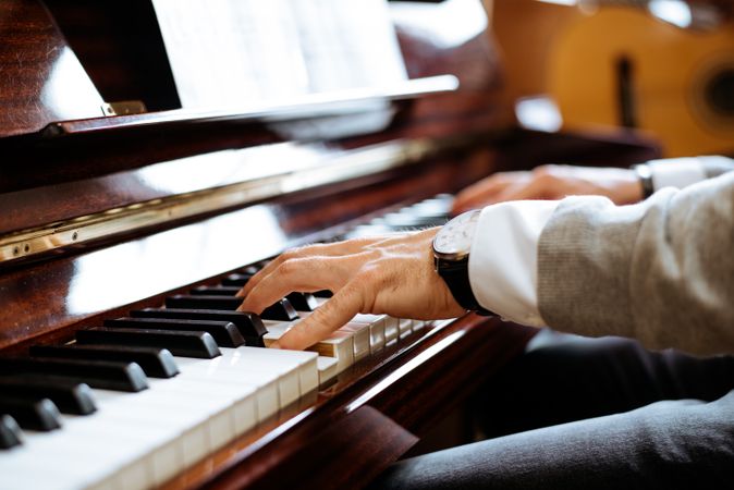 Crop male hands playing piano