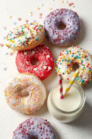 Milk and tasty donuts on plain background