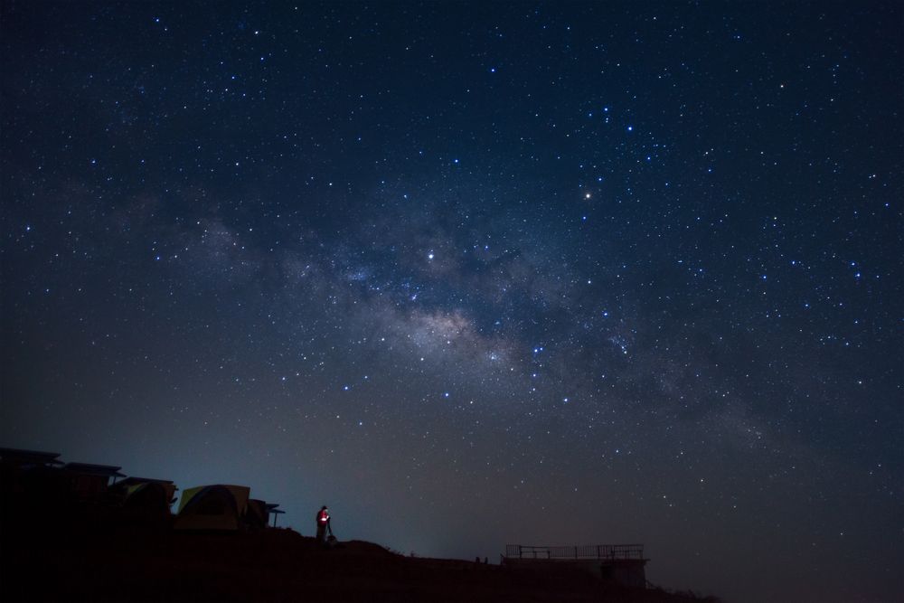 Landscape with milky way, Night sky with stars and silhouette of a standing man on Phutabberk Phetchabun in Thailand