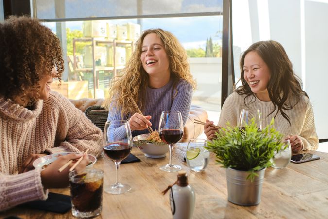 Happy multiracial females chatting during lunch in cafe