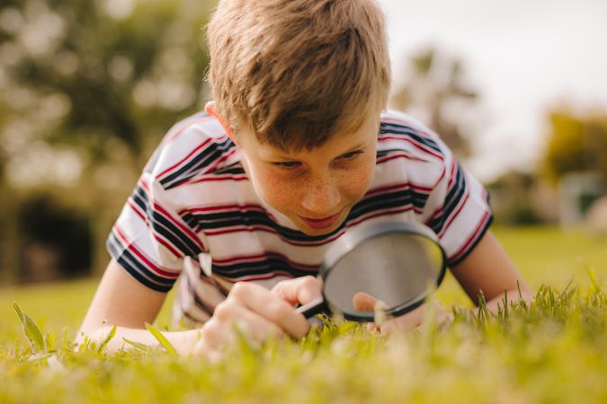 Boy looking at grass through magnifying glass